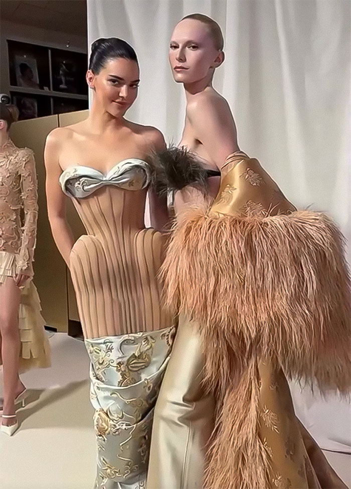 Kendall Jenner in a sheer dress during Paris Fashion Week, posing with another model in a fur-adorned outfit.