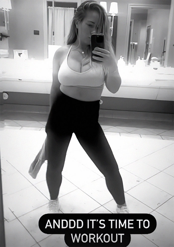 Former model in workout attire taking a mirror selfie in a tiled bathroom with a motivational caption.