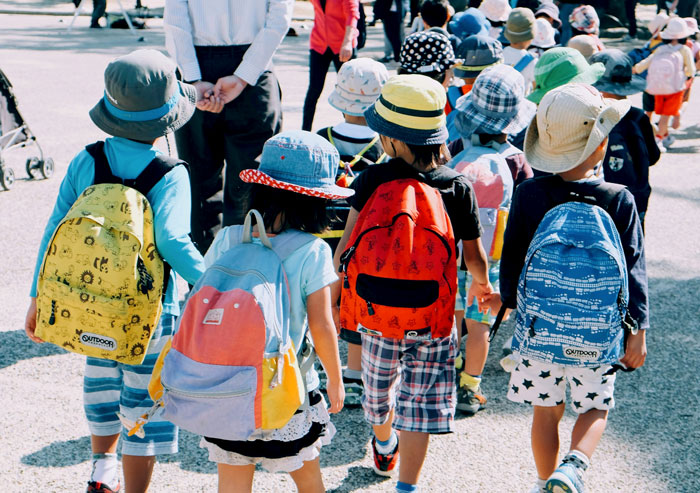 Children with colorful backpacks walking in a line, exploring a foreign country.