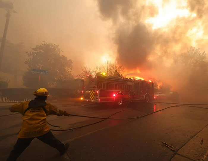 Firefighter battles intense blaze in LA, highlighting wildfire tragedy causes.