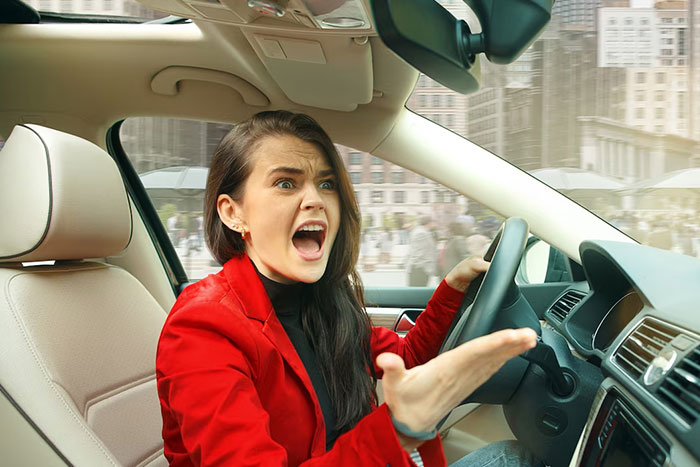 Person in a red jacket looking frustrated while driving, related to wise observations.