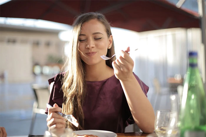 Woman enjoying a meal outdoors, representing wise observations of savoring life's moments.