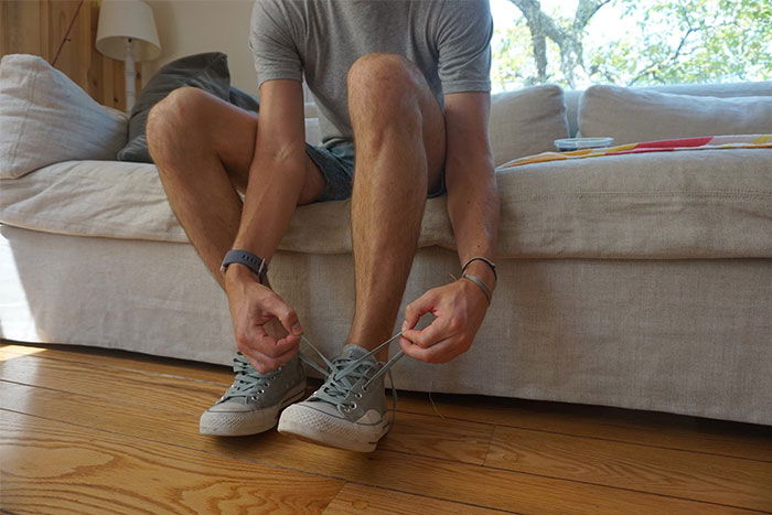 Person tying shoelaces while sitting on a sofa, reflecting on wise observations.