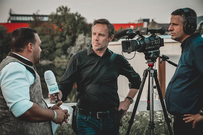 Three men recording an interview outdoors, sharing their wise observations on camera.