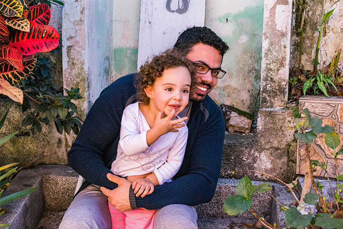 Man and child sitting on stone steps, smiling happily, surrounded by plants, embodying wise observations on life.