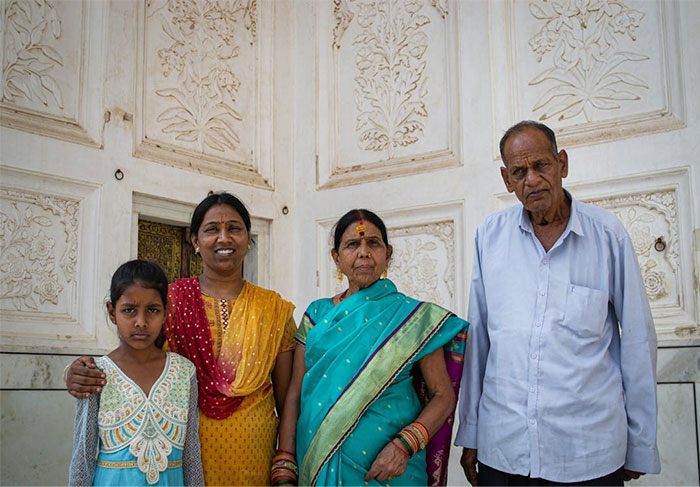 A family of four standing together, showcasing their diverse cultural attire, embodying people's wise observations on life.