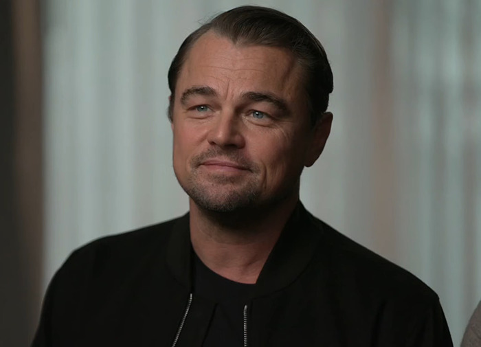 Leonardo DiCaprio in a black outfit indoors.