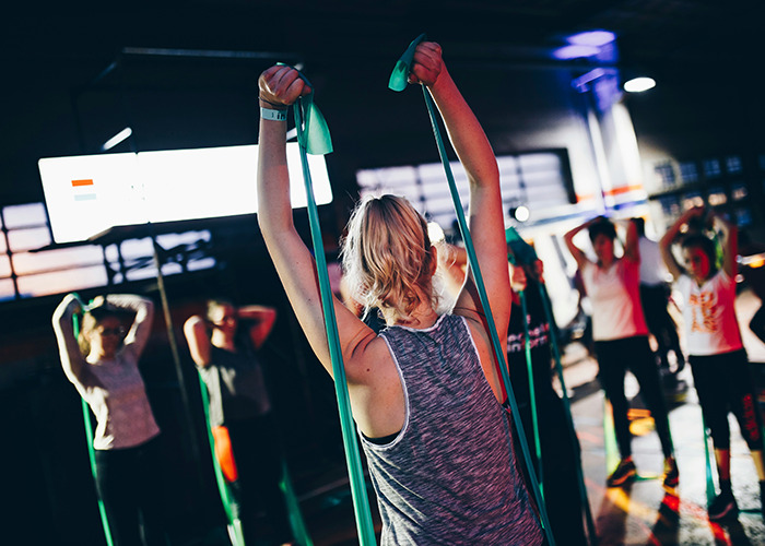 People exercising indoors with resistance bands, demonstrating health hacks for fitness.