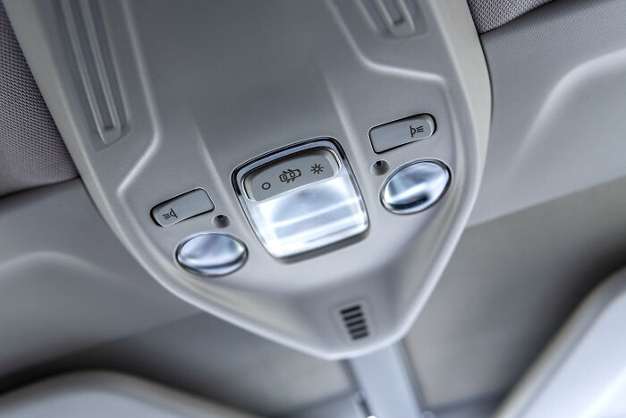 Close-up of a car's overhead console with light and speaker buttons, possibly linked to millennials' adulthood challenges.