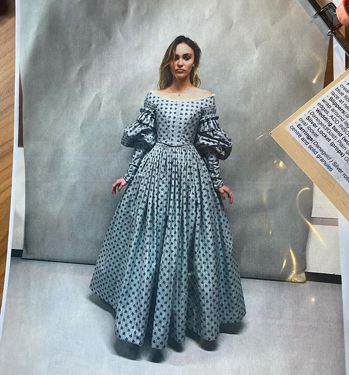 Woman in a patterned gown stands against a plain background, reflecting a vintage audition look.