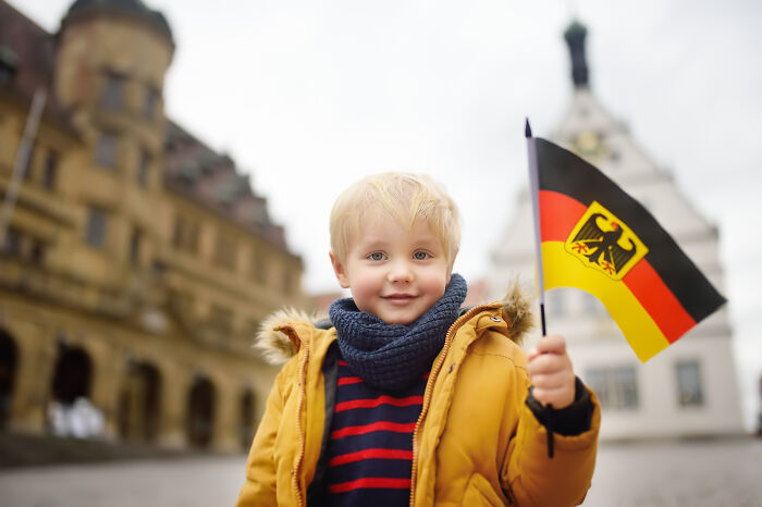 A child holding a German flag, symbolizing kids feeling like foreigners in a different country.