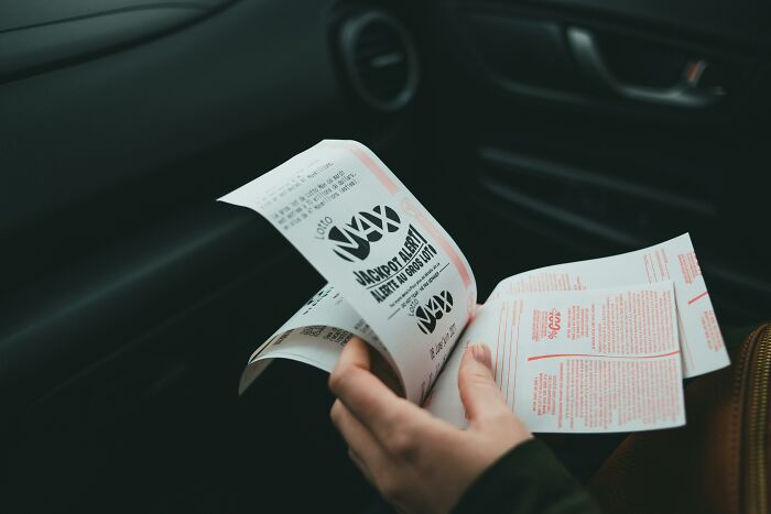 Person holding lottery tickets in a car, illustrating tips for handling lottery wins.