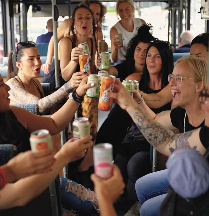 Moms celebrating with drinks on a party bus, redefining nightlife in post-baby era.