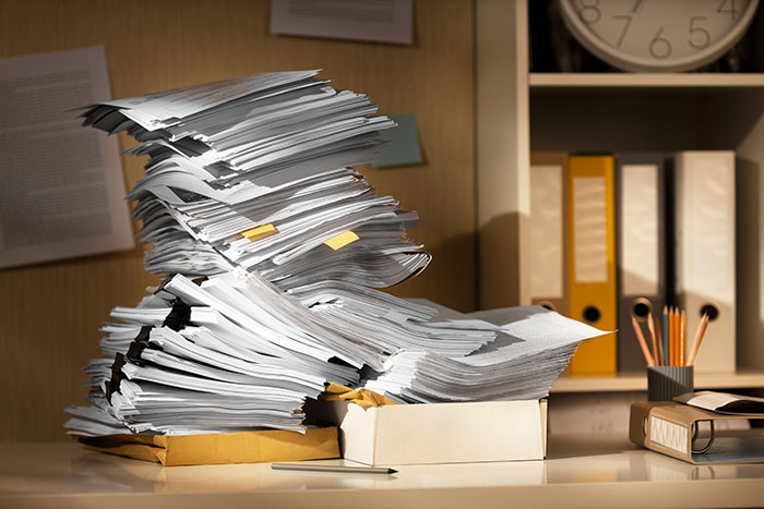 Stack of papers on a desk, surrounded by folders and stationery, possibly related to infidelity accusations.