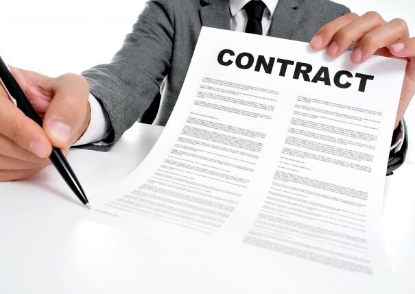 man-in-suit-holding-contract-and-pen.jpg