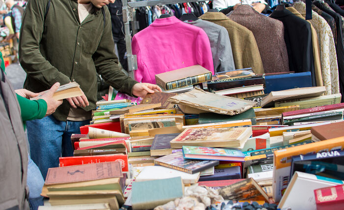 People browsing vintage books with jackets in the background.