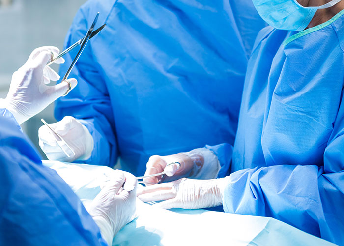 Surgeons in blue scrubs performing a C-section procedure in an operating room.