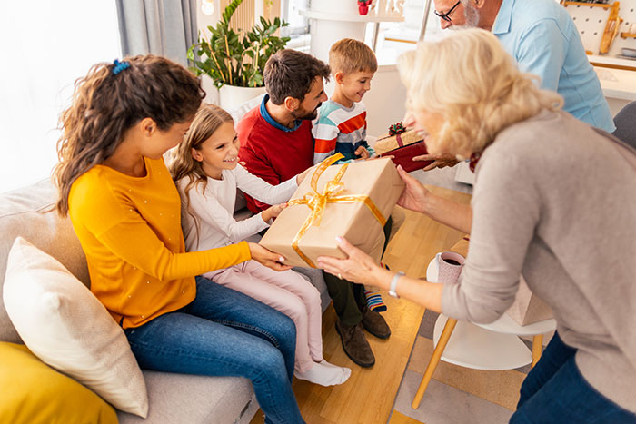 Family exchanging gifts during a white elephant event in a cozy living room.