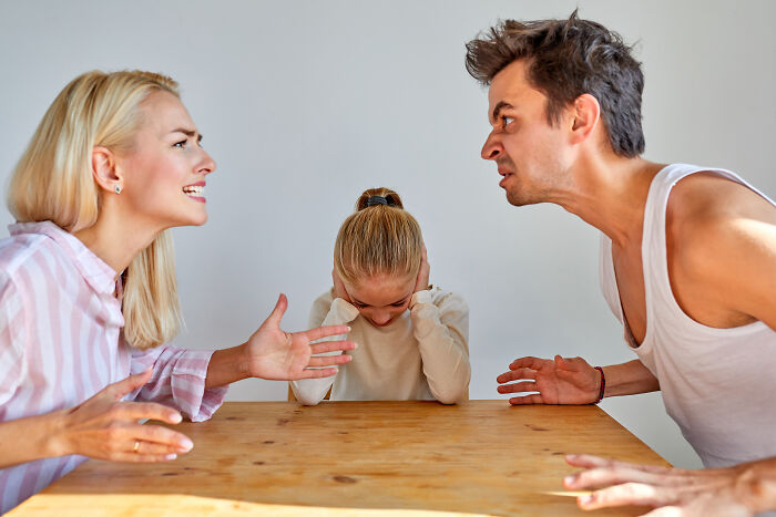 Parents arguing with upset child in the middle, illustrating horrible parenting.