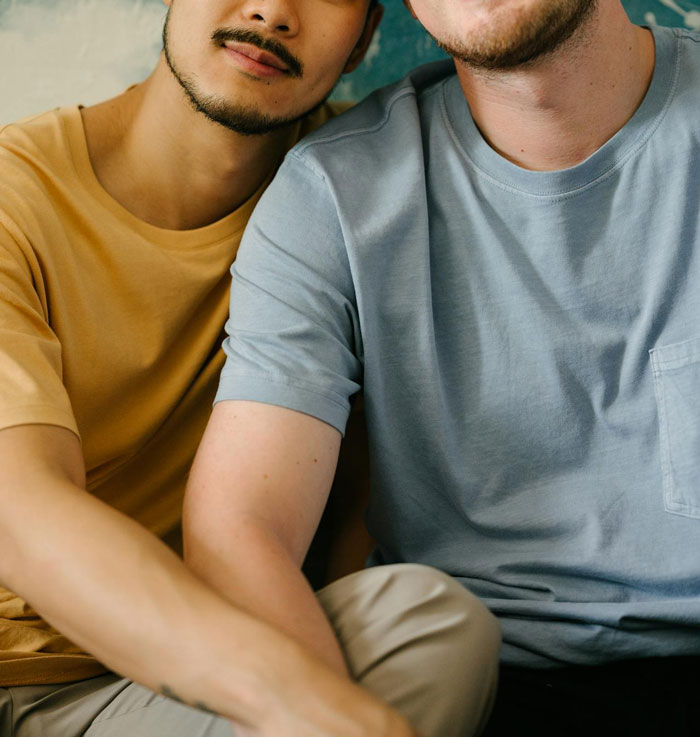 Two men sitting close together, one in a tan shirt, highlighting relationship and trust themes.