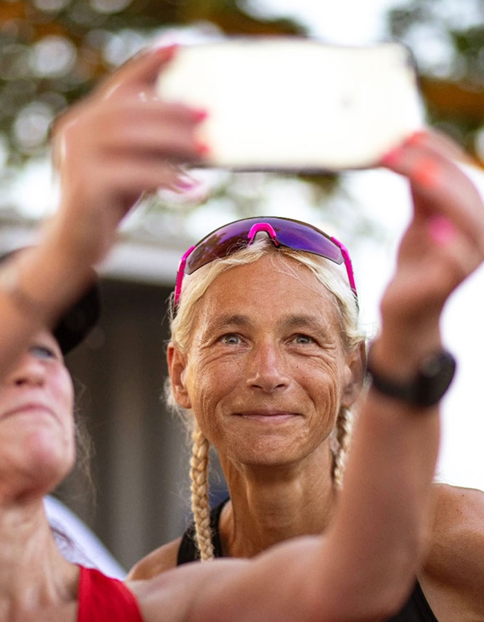 55-year-old woman smiling while taking a selfie, wearing sporty attire after setting a record for marathons in a year.