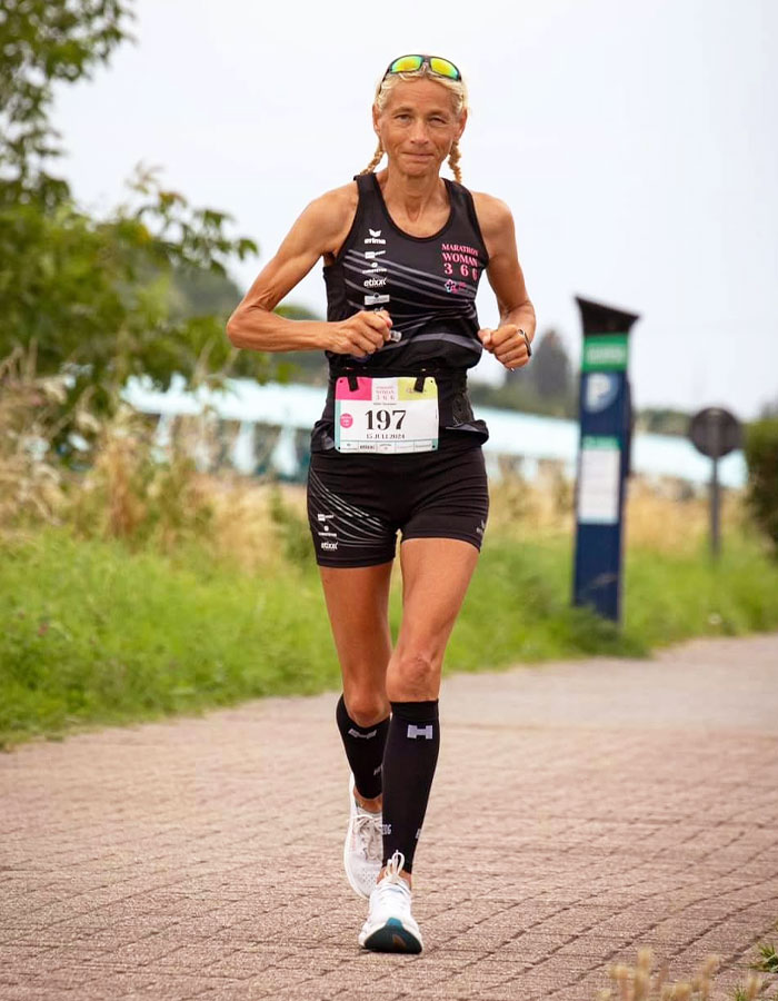 55-year-old woman running a marathon, wearing a black athletic outfit, setting a world record.