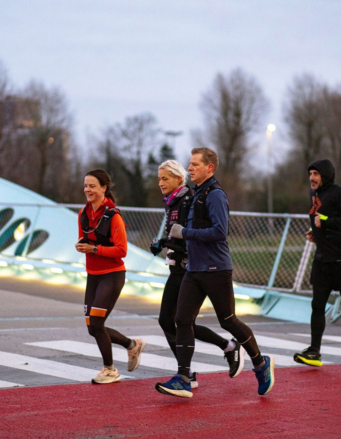 55YO woman sets world record running a marathon, jogging with a group on a bridge.