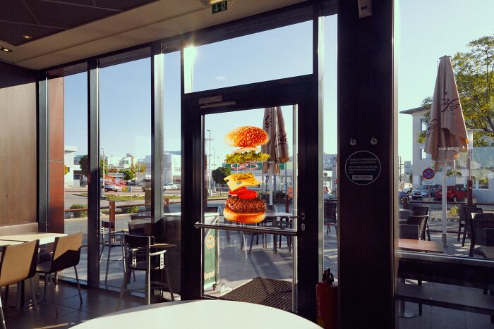 Savage job exit with burger stickers stacked on restaurant door in sunlight.