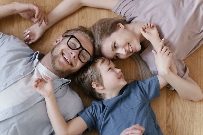 Family lying on the floor, smiling, symbolizing kids feeling like foreigners in different countries.