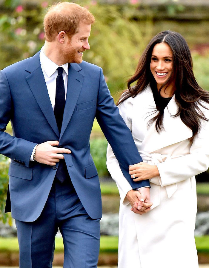 Meghan Markle smiling with her partner in formal attire, outside.