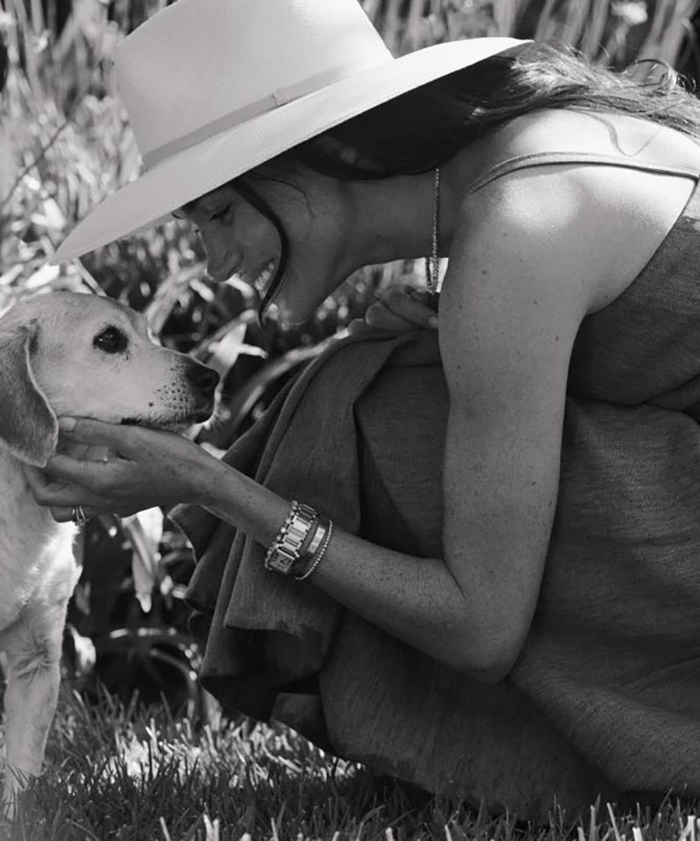 Celebrity smiling at a dog in a garden, wearing a hat, during La wildfires.