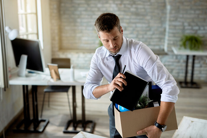 Man packing office belongings in a box, illustrating resume red flags impacting career starts.