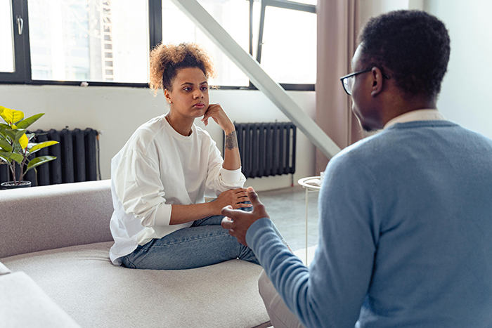 Woman and man discussing the need for a paternity test in a living room setting.