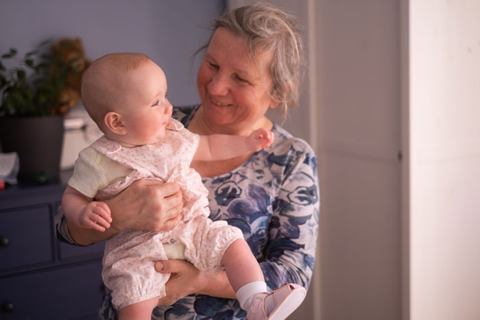 Smiling woman holding a baby in her arms, both appearing happy.