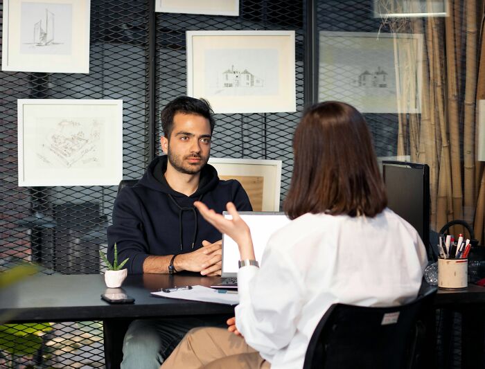 Two people in a professional setting discussing resume red flags across a desk with decor in the background.