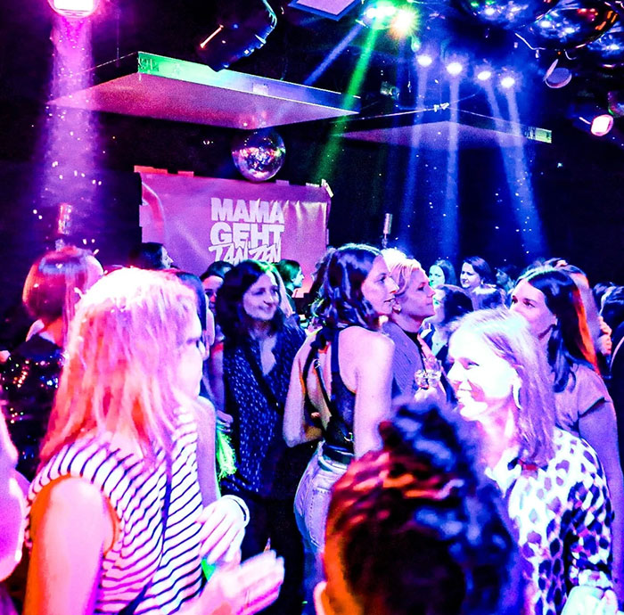 Moms enjoying a vibrant nightclub party, redefining nightlife after kids are asleep, with colorful lights and lively atmosphere.