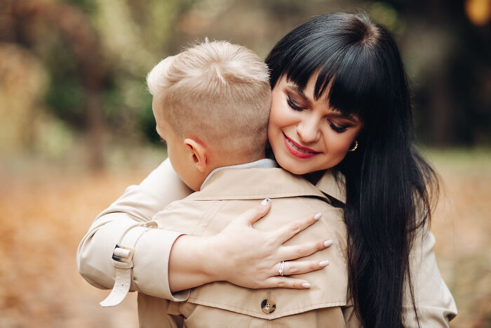 A woman and child hugging outdoors, expressing happiness in a serene setting.