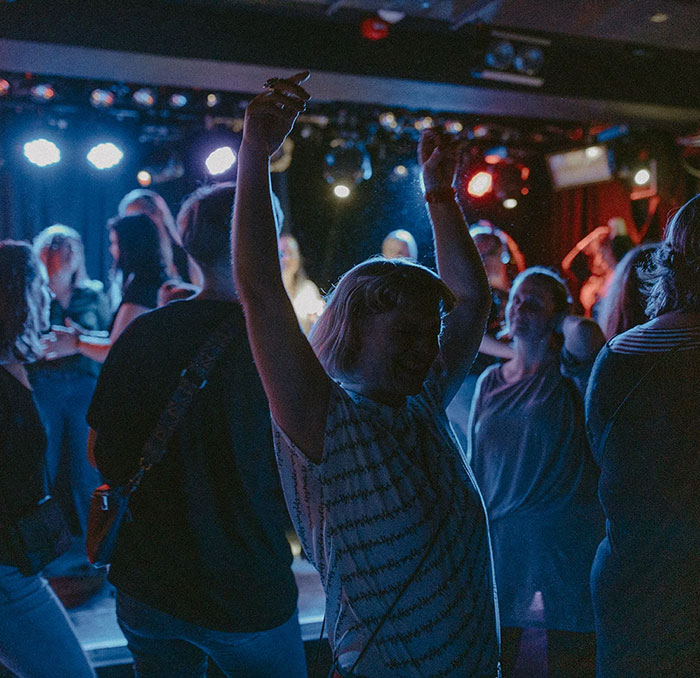 People dancing in a nightclub with vibrant lights, redefining partying after having kids.