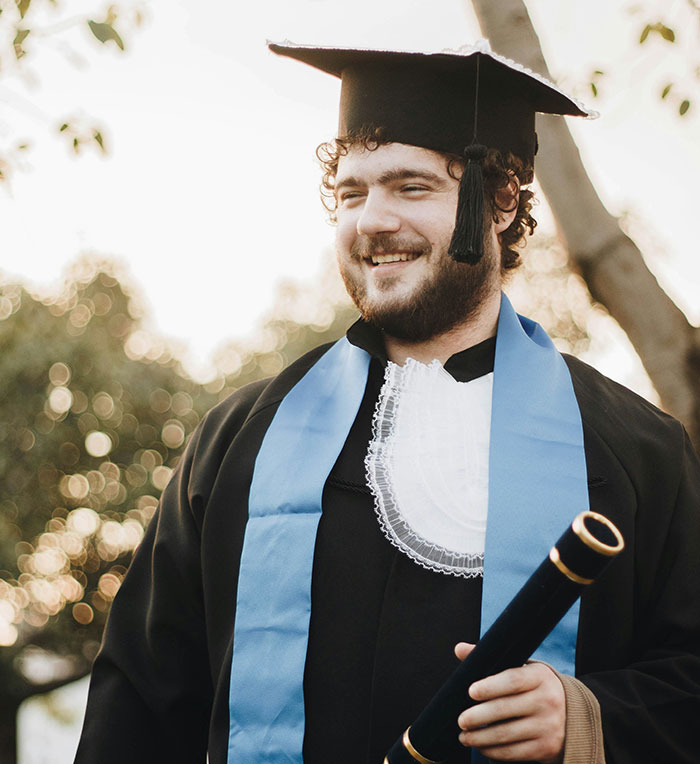 Graduation day with a smiling graduate in cap and gown, holding a diploma, symbolizing touching achievements.