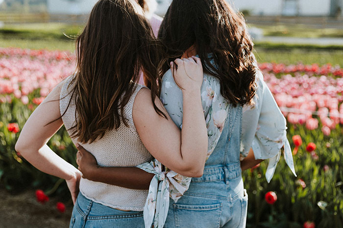 Two women embracing in a field of tulips, symbolizing touching moments and connection.