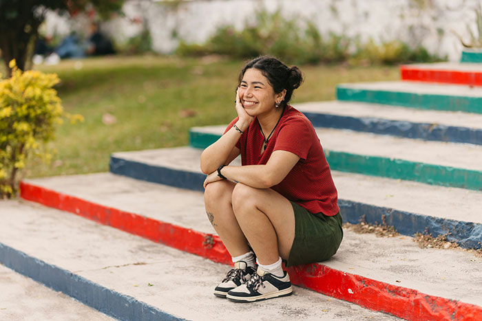 A person smiling warmly while sitting on colorful steps, representing touching moments shared.