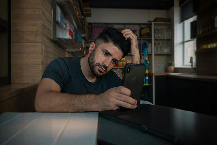 A thoughtful person sitting indoors, reflecting on touching words, holding a phone.