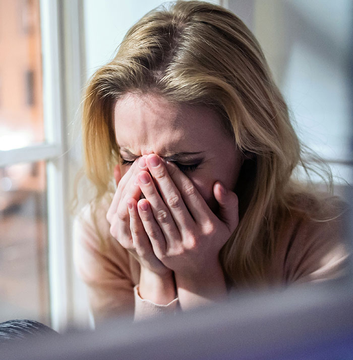 Woman overcome with emotion, hands covering face, reacting to touching words.