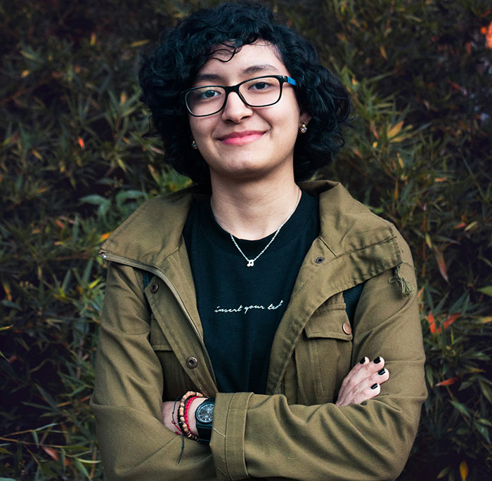 Person smiling with arms crossed, wearing glasses and a green jacket, representing touching moments shared by people.