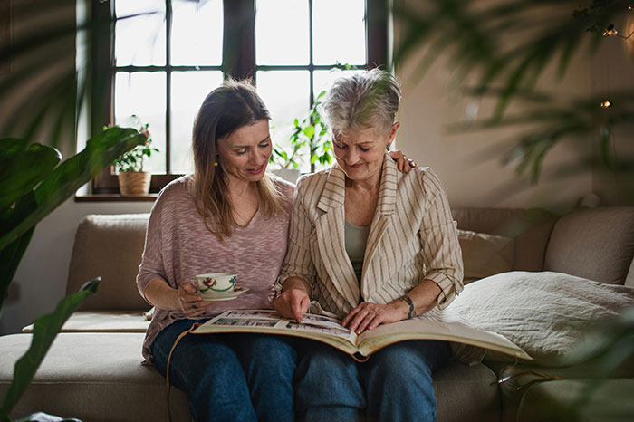 Two people sharing a touching moment, looking at a photo album on a cozy sofa.