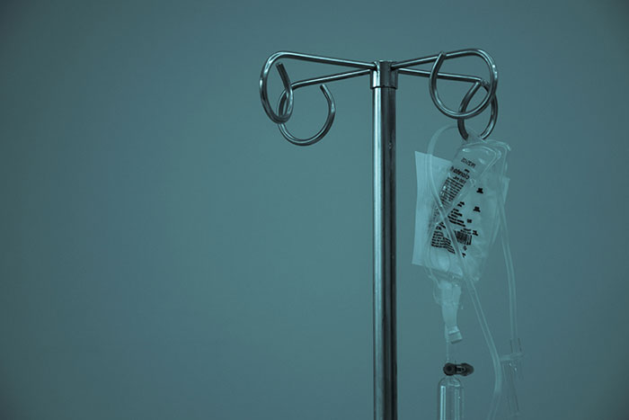 IV drip stand with a fluid bag attached, symbolizing a touching moment of care in a medical setting.