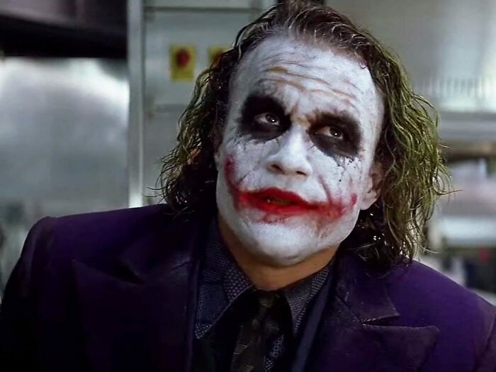 Character with white makeup and smeared red lips, wearing a dark suit, capturing a memorable celebrity portrayal.