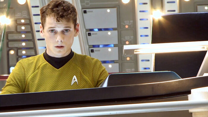 Actor in a yellow Star Trek uniform on a futuristic set, reminiscent of celebrity deaths that impacted many.