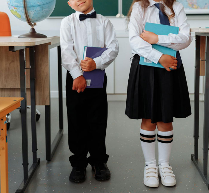 Children in school uniforms standing in a classroom, reflecting a dress code compliance theme.