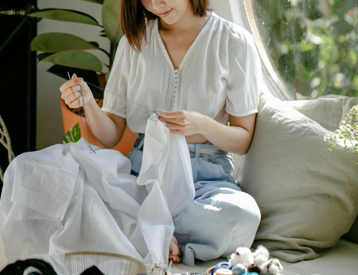 A mom sewing a dress, demonstrating school dress code loophole compliance, sitting in a sunlit room.